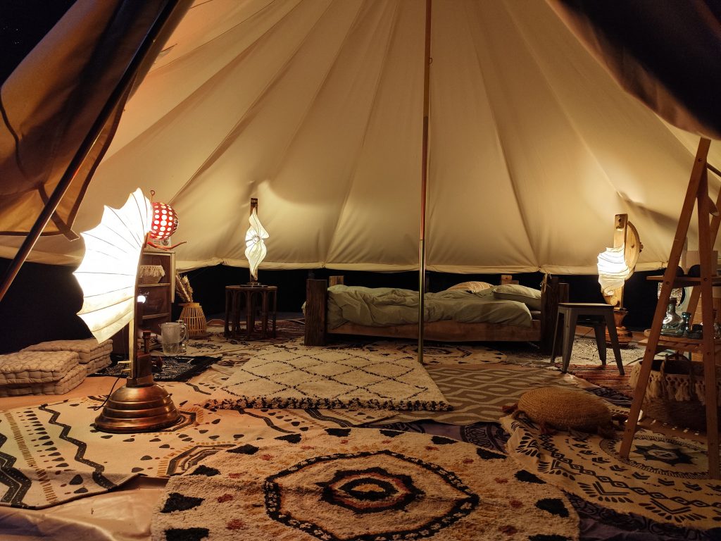 Intérieur cosy tente insolite 6m diamètre avec trois luminaires design en papier japonais Tengucho, lit double et ambiance Wabi-Sabi.